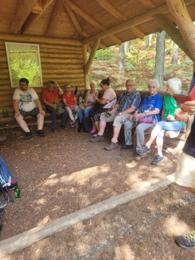Eine Gruppe von Menschen sitzt unter einem Überstand in der Natur.