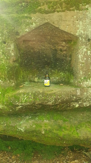 Ein Glas auf einem moosbedeckten Felsen in einer natürlichen Nische.