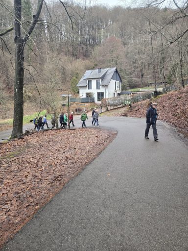 Eine Gruppe von Menschen geht einen Weg zu einem weißen Haus in der Natur.