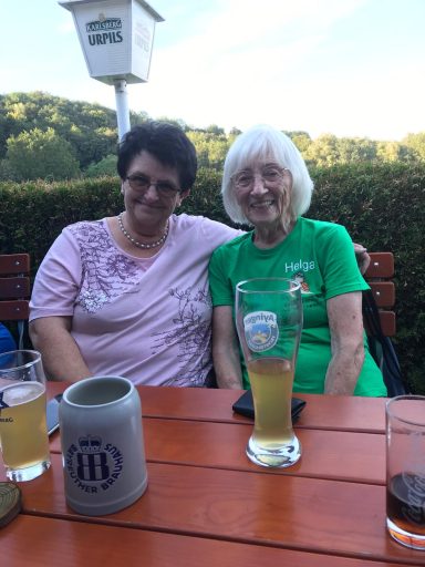 Zwei Frauen sitzen an einem Tisch, umgeben von Getränken und Natur.