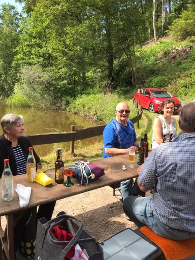 Gruppe von Menschen beim Picknick an einem ruhigen Flussufer in der Natur.