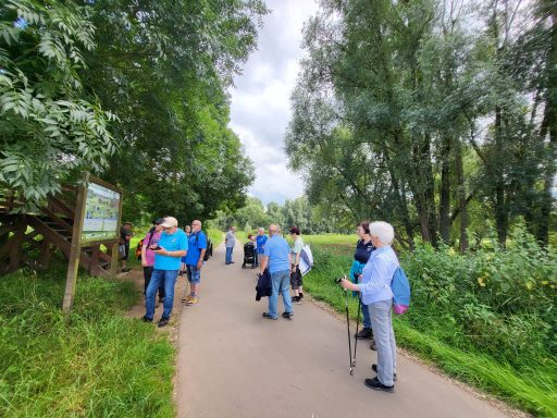 Gruppe von Menschen auf einem Spaziergang entlang eines schmalen Wegs durch die Natur.