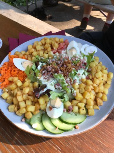 Bunte Salatschüssel mit Mais, Gurken, Karotten, Eiern und einer cremigen Sauce.